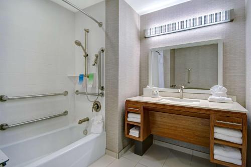 ein Badezimmer mit einer Badewanne, einem Waschbecken und einem Spiegel in der Unterkunft Home2 Suites Dallas-Frisco in Frisco