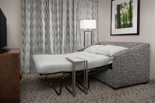 a room with a bed and a table and a lamp at Embassy Suites Springfield in Springfield