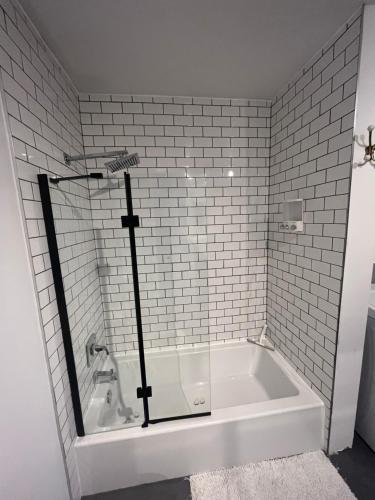 La salle de bains est pourvue d'une baignoire et de carrelage blanc. dans l'établissement Gite - La ruée vers l'orge, à Trois-Rivières