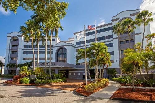 un hôtel avec des palmiers devant lui dans l'établissement DoubleTree by Hilton Hotel West Palm Beach Airport, à West Palm Beach