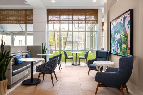 Hampton Inn & Suites San Juan في سان خوان: منطقة انتظار مع طاولات وكراسي ونوافذ
