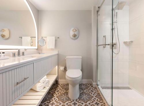 uma casa de banho branca com um WC e um chuveiro em The Singer Oceanfront Resort, Curio Collection by Hilton em Palm Beach Shores