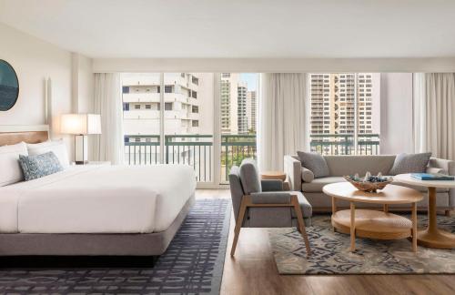 1 dormitorio con 1 cama extragrande y sala de estar en The Singer Oceanfront Resort, Curio Collection by Hilton, en Palm Beach Shores