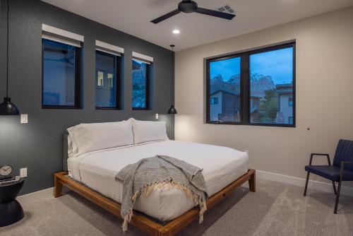 a bedroom with a bed with a ceiling fan and windows at LaFave Luxury Rentals at Zion in Springdale