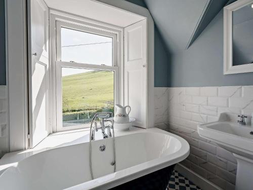 La salle de bains est pourvue d'une baignoire blanche et d'une fenêtre. dans l'établissement 3 Bed in Biggar 82924, à Biggar