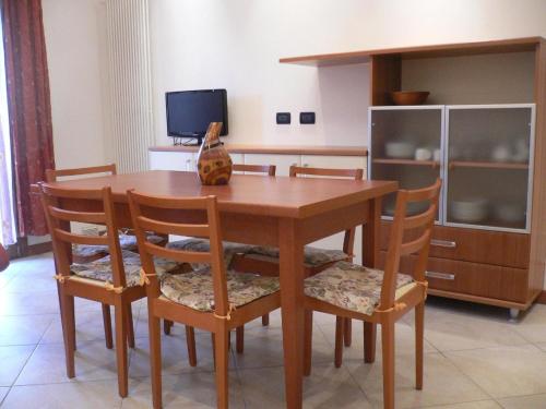 une table à manger en bois avec des chaises et une télévision dans l'établissement Große Wohnung in Rosolina Mare mit Grill und Garten, à Rosolina Mare