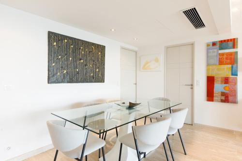 une salle à manger avec une table en verre et des chaises blanches dans l'établissement Élégant appartement 120m² en front de mer à Cannes, à Cannes