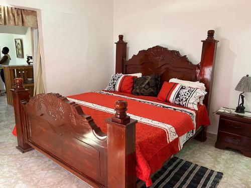 a bedroom with a large wooden bed with red sheets at Apartamento Carmen in Santa Cruz de Barahona