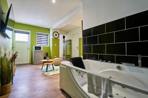 La salle de bains est pourvue d'une grande baignoire et de murs verts. dans l'établissement NG Prestige - Lille l Roubaix Trichon - Balnéo - Netflix - Wifi, à Roubaix