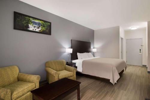 une chambre d'hôtel avec un lit et deux chaises dans l'établissement Quality Inn Columbia, à Columbia
