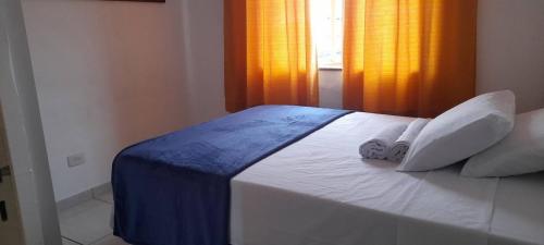 un dormitorio con una cama con sábanas y almohadas blancas en Apartamento em Ubatuba- centro - apartamento 2 quartos com ar cond, en Ubatuba