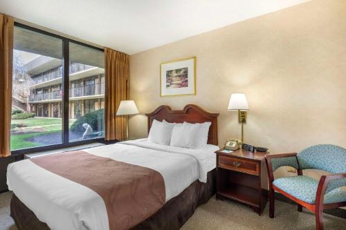 um quarto de hotel com uma cama e uma cadeira e uma janela em Quality Inn Vienna - Tysons Corner em Tysons Corner
