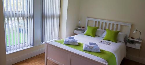 a bedroom with a bed with green pillows on it at Chandler's Lodge B&B in Camelford