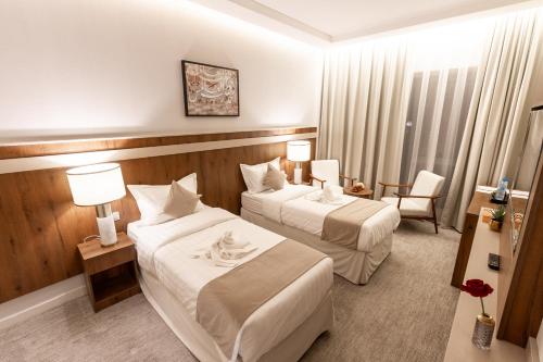 una habitación de hotel con 2 camas y una silla en Wassad Hotel Makkah فندق وسد مكة, en La Meca