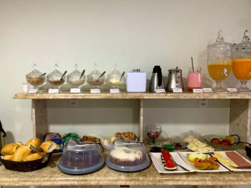 ein Regal mit verschiedenen Speisen und Getränken in der Unterkunft Hotel Flat Almaru - Marília in Marília
