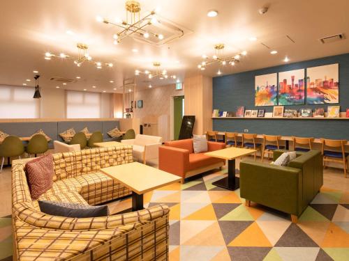 a waiting room with couches and tables and chairs at Comfort Hotel ERA Kobe Sannomiya in Kobe