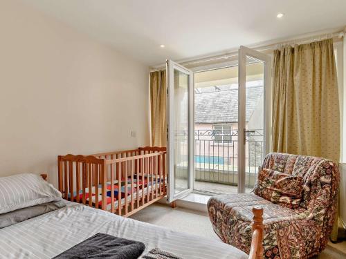 a bedroom with a crib and a chair next to a crib at 3 Bed in Tenby FB053 in Tenby
