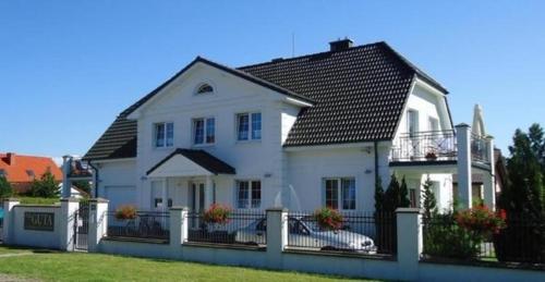a white house with a black roof and a fence at Gemütliche Wohnung in Rowy mit Terrasse, Grill, Parkplatz und Garten in Rowy