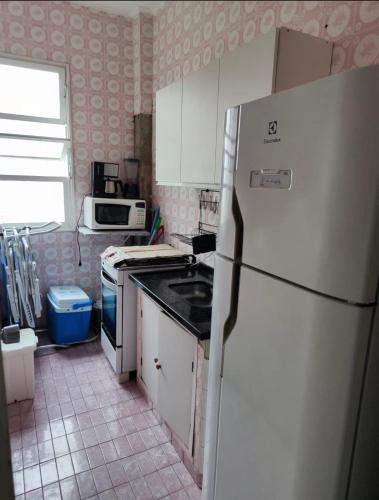 a kitchen with a white refrigerator and a tile floor at Pé na Areia em Santos in Santos