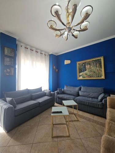 een blauwe woonkamer met banken en een kroonluchter bij Xplore Xpress • Penthouse in Tirana