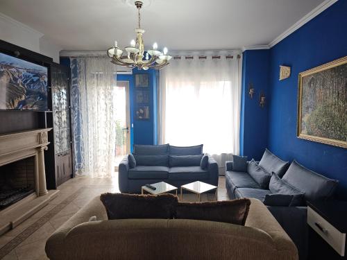 een blauwe woonkamer met banken en een kroonluchter bij Xplore Xpress • Penthouse in Tirana