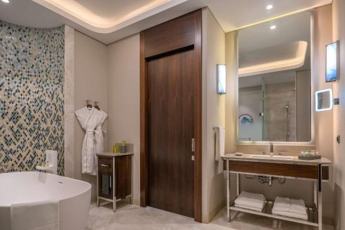 a bathroom with a tub and a sink and a mirror at Hilton Tashkent City in Tashkent