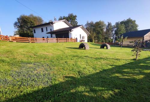 a field with a white house and a fence at Ferienwohnung Casa Bianka in Fridolfing in Fridolfing