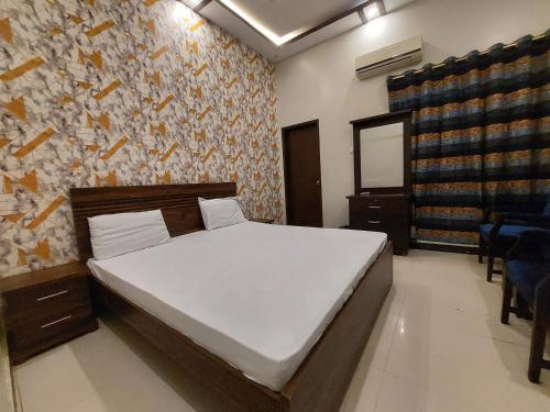 a bedroom with a bed and a stone wall at Karachi Guest House in Karachi