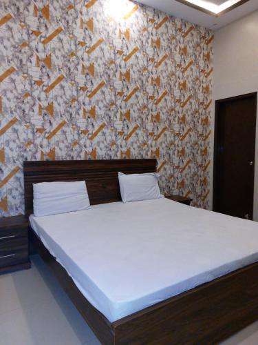a bedroom with a large bed and a wall at Karachi Guest House in Karachi