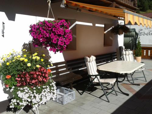 a patio with a table and chairs and flowers at Pension Elisabeth in Vent