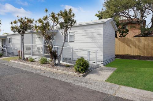 a white house with palm trees in a yard at Reflections Ballina - Holiday Park in Ballina