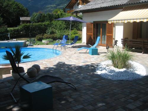 un patio con sillas y una piscina en Geräumige Ferienwohnung mit zwei Schlafzimmern, ideal für eine Familie, en Flattach