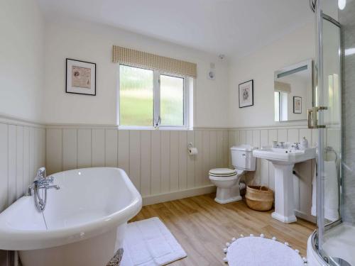 a bathroom with a tub and a sink and a toilet at 3 Bed in Llanrhaeadr Ym Mochnant 85799 in Llanrhaeadr-ym-Mochnant
