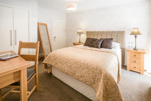 a bedroom with a bed and a table and a desk at Queenshead Hotel Kelso in Kelso