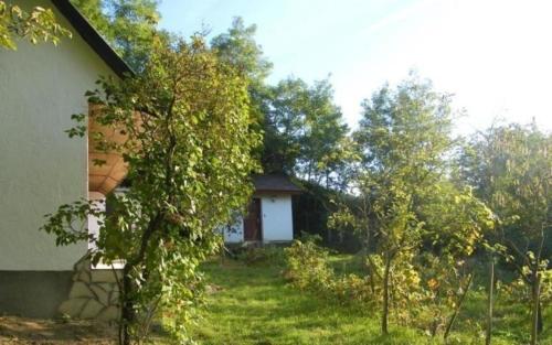 ein Haus mit einem Garten mit Bäumen davor in der Unterkunft Komfortables Ferienhaus in den Weinbergen, bei absolut ruhiger Lage - ideal zur Erholung in der Natur in Döbrököz