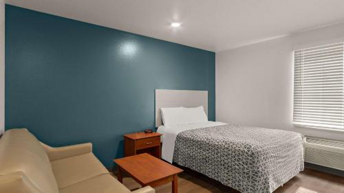 a bedroom with a bed and a blue wall at WoodSpring Suites Evansville in Evansville