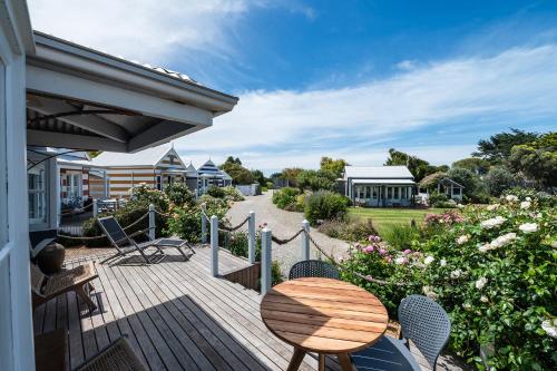 a wooden deck with a table and chairs on a house at Beach Huts Middleton in Middleton