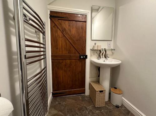 uma casa de banho com uma porta de madeira e um lavatório em The Cosy Cottage Retreat! Perfect for Contractors, Relocators, Getaway em Llantrisant