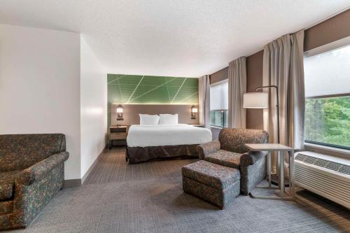 レイク・ジョージにあるComfort Inn & Suitesのベッド1台と椅子2脚が備わるホテルルームです。