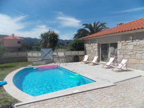 a swimming pool with chairs and a house at Casa Silva Do Minho in Arcos de Valdevez