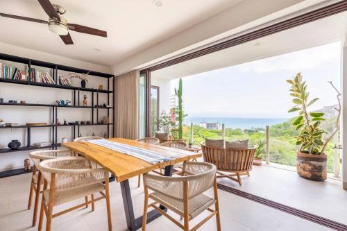 a dining room with a table and chairs and a large window at Jungle by Pardela, La Cruz de Huanacaxtle in Cruz de Huanacaxtle