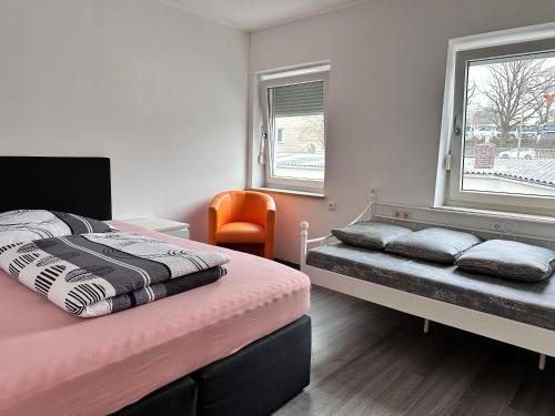 1 dormitorio con 2 camas y silla naranja en Ferienwohnung J8, Playmobil Funpark Zirndorf Nürnberg, en Zirndorf