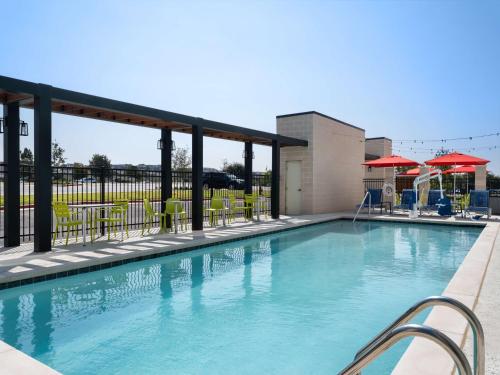 a swimming pool at a hotel with chairs and umbrellas at Home2 Suites By Hilton Round Rock Medical Center in Round Rock