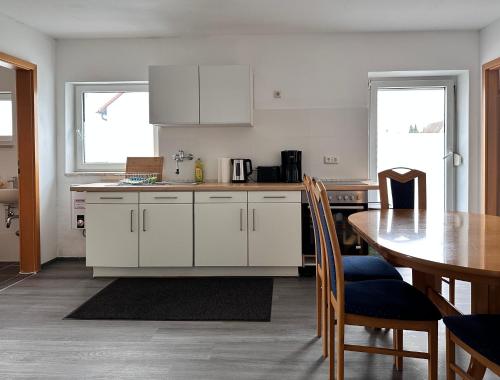 a kitchen with white cabinets and a table and a table and chairs at Ferienwohnung J8, Playmobil Funpark Zirndorf Nürnberg in Zirndorf