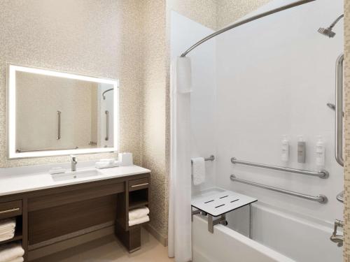 a bathroom with a sink and a tub and a mirror at Home2 Suites By Hilton Round Rock Medical Center in Round Rock