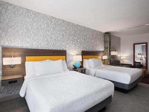 a hotel room with two beds and a desk and a room with two bedsskirts at Home2 Suites By Hilton Round Rock Medical Center in Round Rock
