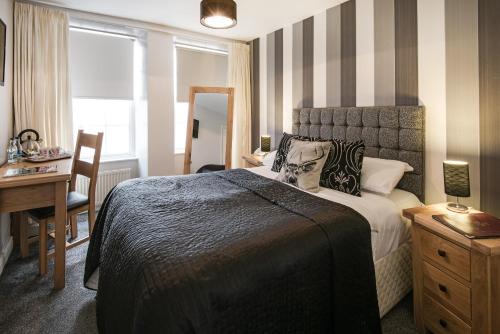 a hotel room with a bed and a desk and a window at Queenshead Hotel Kelso in Kelso