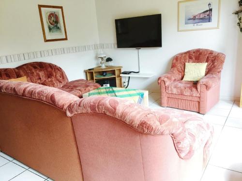a living room with two pink chairs and a couch at Gemütlicher Ferienbungalow mit Garten in Hechthausen