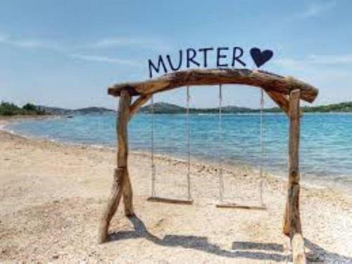 un columpio en una playa con un cartel que dice invierno en Strandnahes, ruhig gelegenes Ferienhaus mit eigenem Pool auf der Insel Murter, en Murter