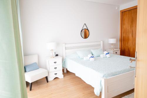 a bedroom with a white bed and a white chair at J&B Place in Ponta Delgada